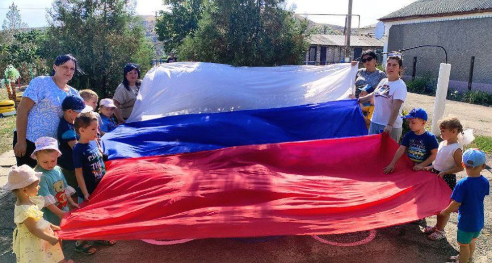 Солнечный денёк, улыбки повсюду, дети смеются, бегают друг за другом и машут маленькими флажками Солнечный денёк, улыбки повсюду, дети смеются, бегают друг за другом и машут маленькими флажками