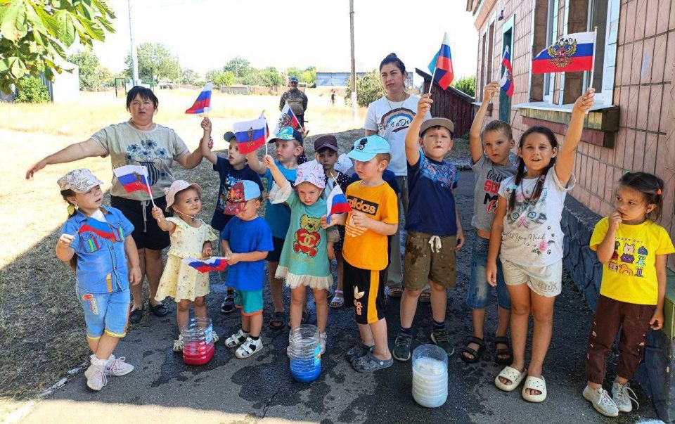 Солнечный денёк, улыбки повсюду, дети смеются, бегают друг за другом и машут маленькими флажками Солнечный денёк, улыбки повсюду, дети смеются, бегают друг за другом и машут маленькими флажками